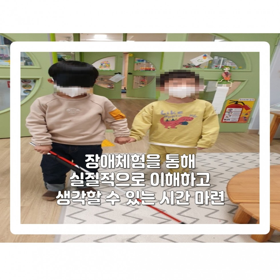 두명의 아이가 서 있는데 한아이는 안대에 흰지팡이를 짚고 시각장애인 체험을 하며 옆에 한아이는 체험을 하는 아이가 다치지 않도록 옆에서 도움을 주는 모습입니다. 얼굴을 모자이크 처리가 되어져 있습니다.